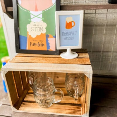 Grab a Stein from the Fraulein printable sign next to glass beer mugs at an adult Oktoberfest party