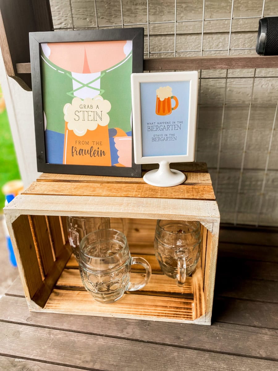Grab a Stein from the Fraulein printable sign next to glass beer mugs at an adult Oktoberfest party