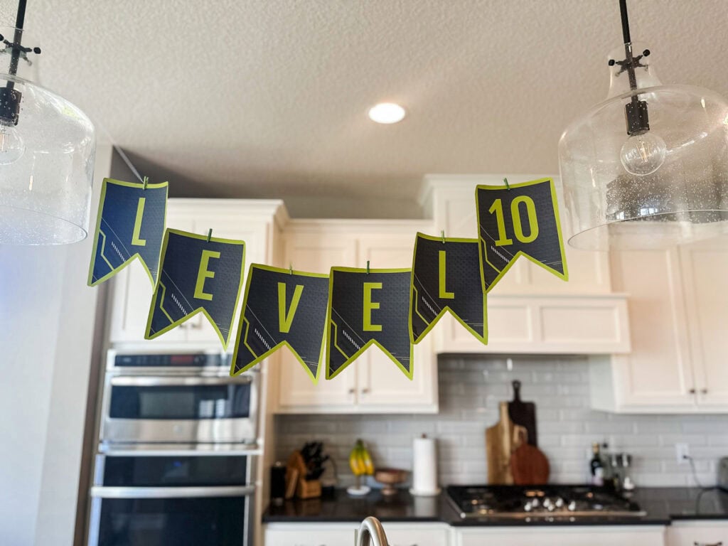 Level 10" dark charcoal and lime green pennant banner hanging above kitchen island at gamer birthday party