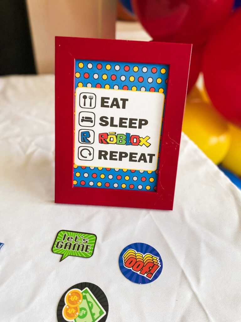 Eat Sleep Roblox Repeat framed printable sign in red frame with blue polka dot background on Roblox birthday party dessert table