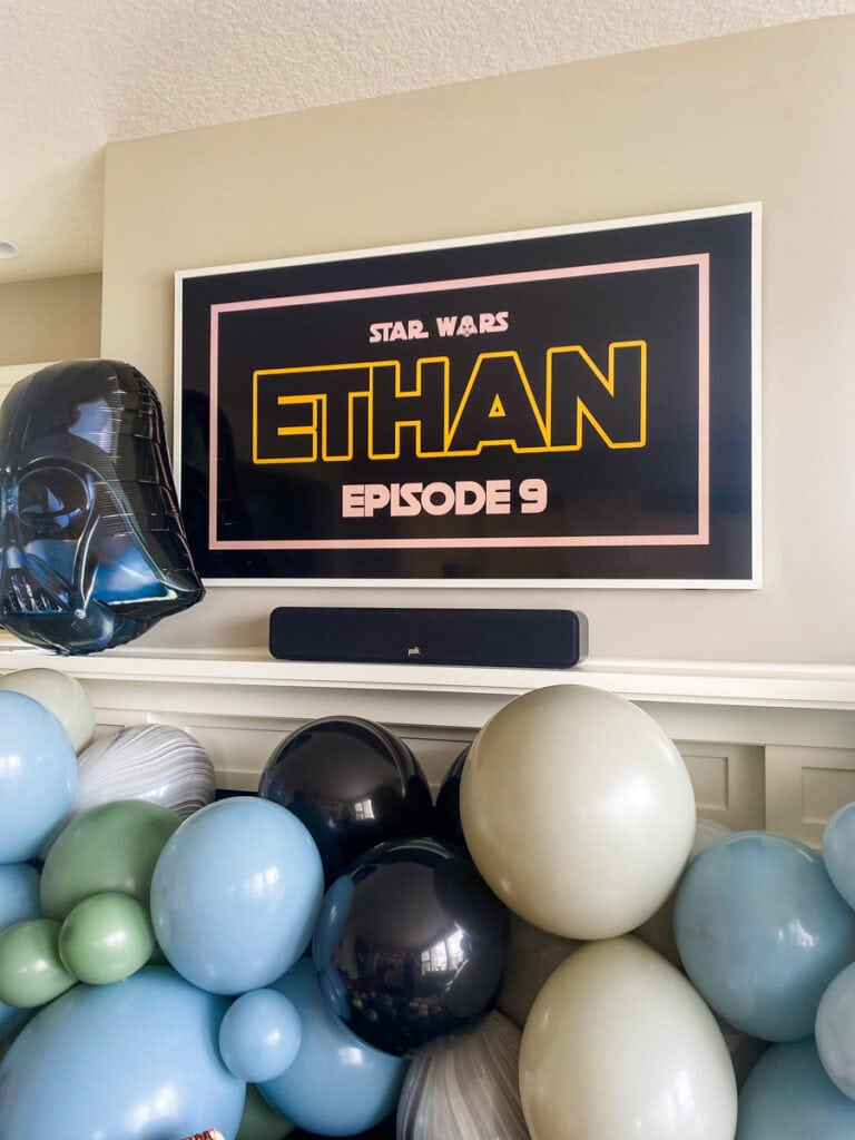 TV displaying Star Wars crawl with muted balloon garland and Darth Vader foil balloon